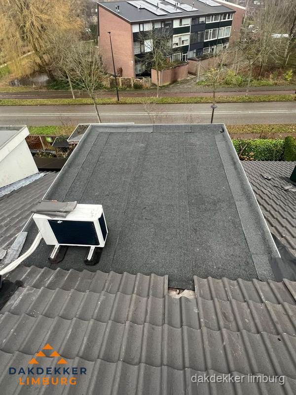 Plat dak inspectie met bitumen bedekking naast schuin pannendak in Limburg