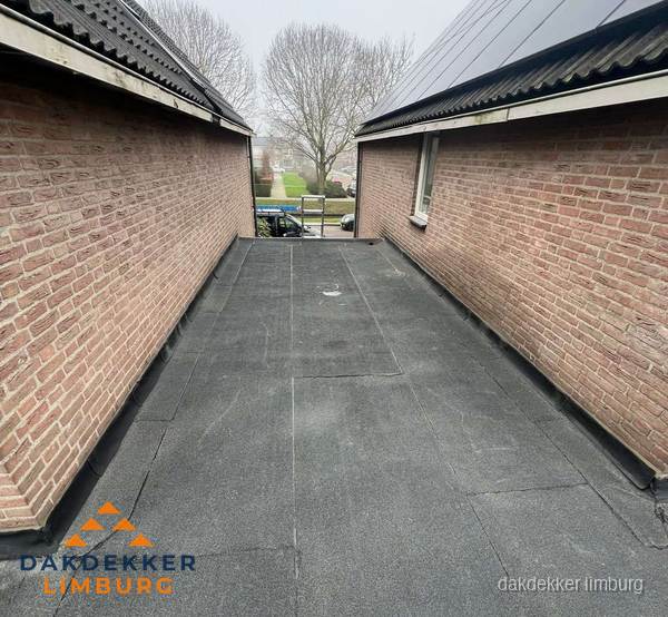 Plat dak met bitumen dakbedekking tussen bakstenen muren in Limburg Plat dak met bitumen dakbedekking tussen bakstenen muren in Limburg