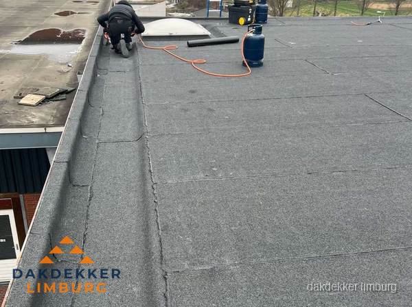 Dakdekker repareert bitumen dakbedekking op groot plat dak in Limburg Dakdekker repareert bitumen dakbedekking op groot plat dak in Limburg